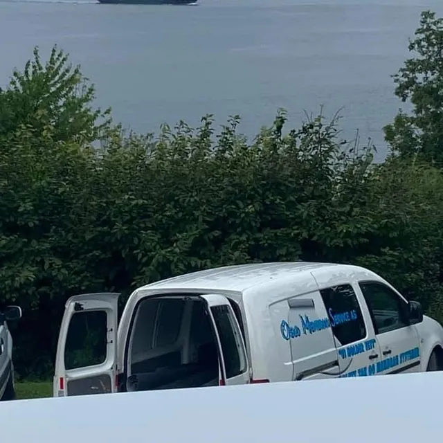 Firmabil med fjord og ferge i bakgrunn